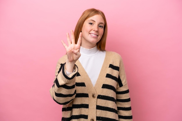 Young redhead woman isolated on pink background happy and counting four with fingers