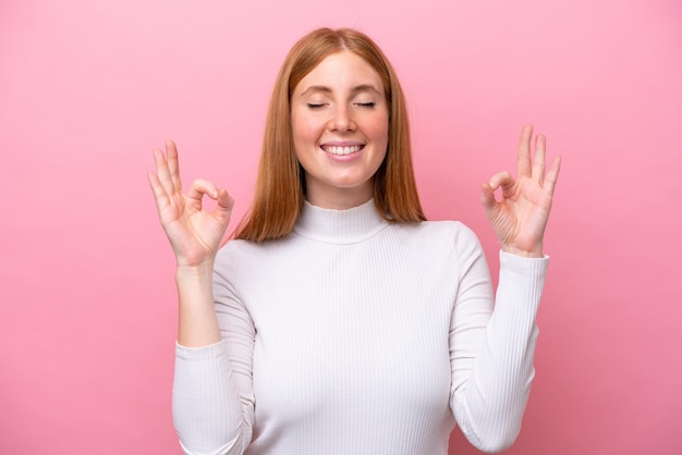 Young redhead woman isolated on pink background in zen pose