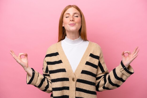 Photo young redhead woman isolated on pink background in zen pose