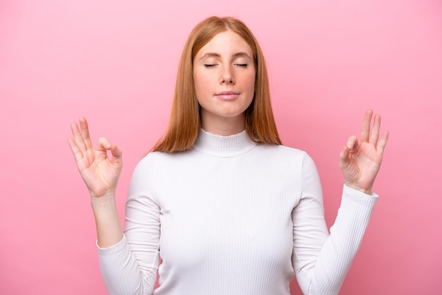 Young redhead woman isolated on pink background in zen pose