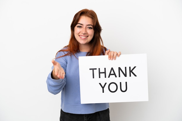 Photo young redhead woman isolated on white background holding a placard with text thank you making a deal