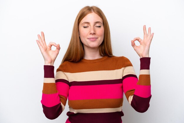 Young redhead woman isolated on white background in zen pose