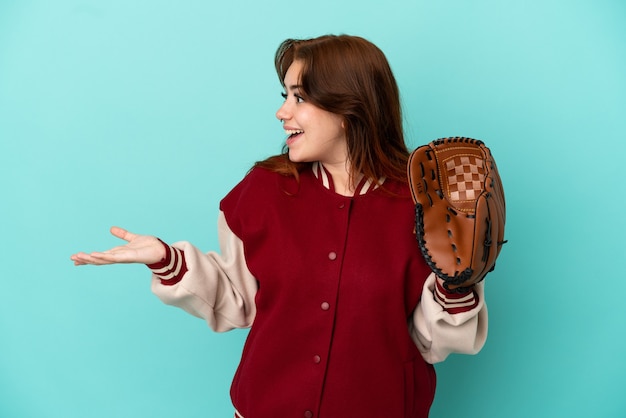 Young redhead woman playing baseball isolated on blue background with surprise expression while looking side