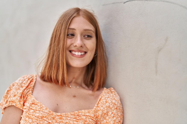 Young redhead woman smiling confident looking to the side over white isolated background