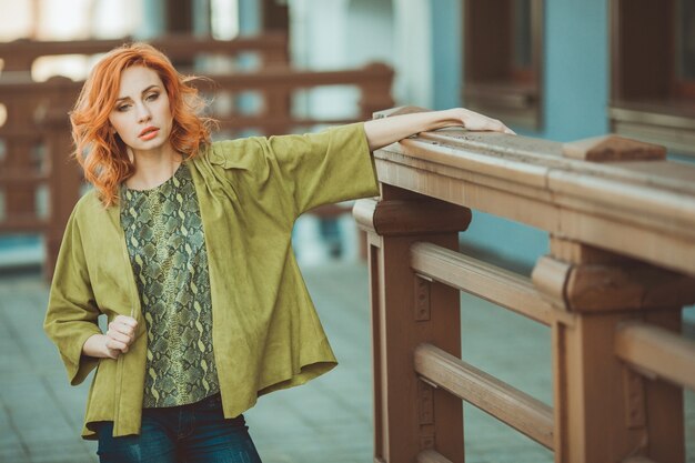 Young redhead woman standing on ground distracted in outdoor setting