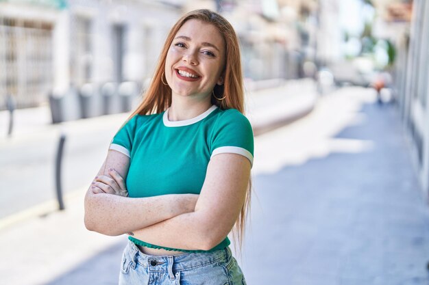 Foto giovane donna rossa in piedi con le braccia incrociate gesto in strada