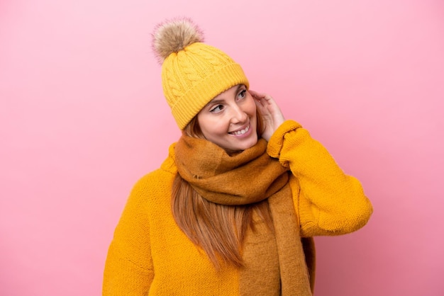 Young redhead woman wearing winter jacket isolated on pink background thinking an idea