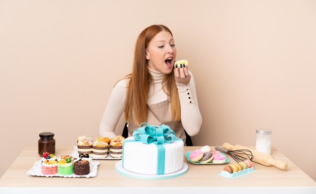 Young redhead woman with a big cake