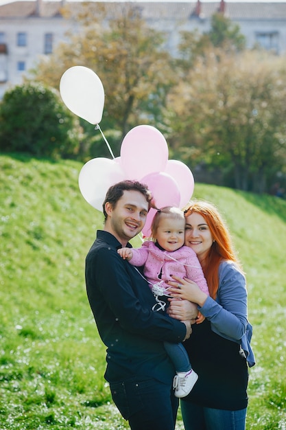 A young redheaded mother plays in the park with her husband and their little daughter