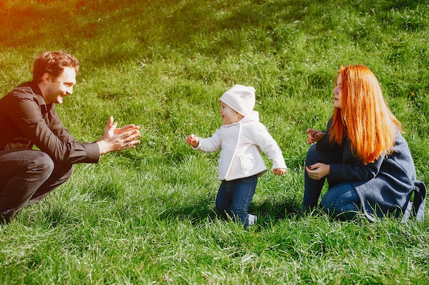 A young redheaded mother plays in the park with her husband and their little daughter