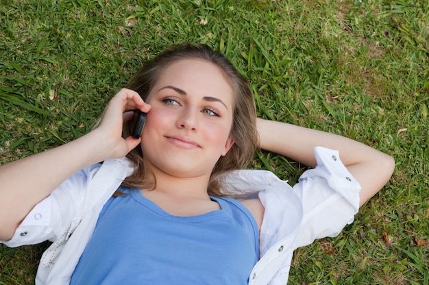 Photo young relaxed blonde girl lying on her back while talking on the phone