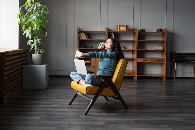 Young relaxed woman doing hand exercises at remote workplace working during covid lockdown