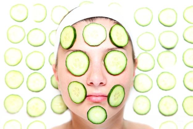 a young relaxed woman with her face covered with cucumber slices