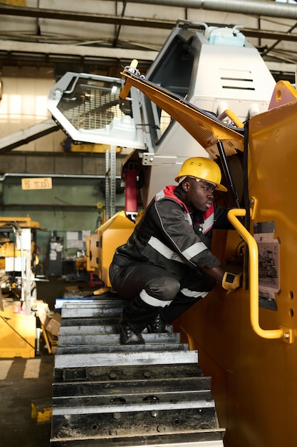 Young repairman checking engine of huge industrial machine