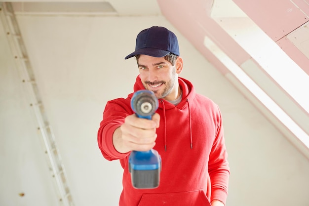 Young repairman with power drill at construction site