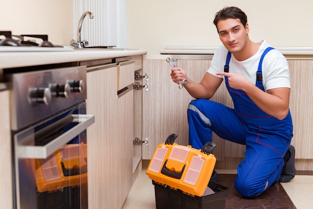 Young repairman working at the kitchen