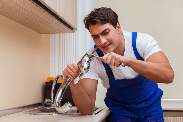 Young repairman working at the kitchen