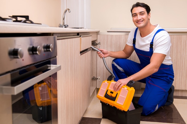 Photo young repairman working at the kitchen