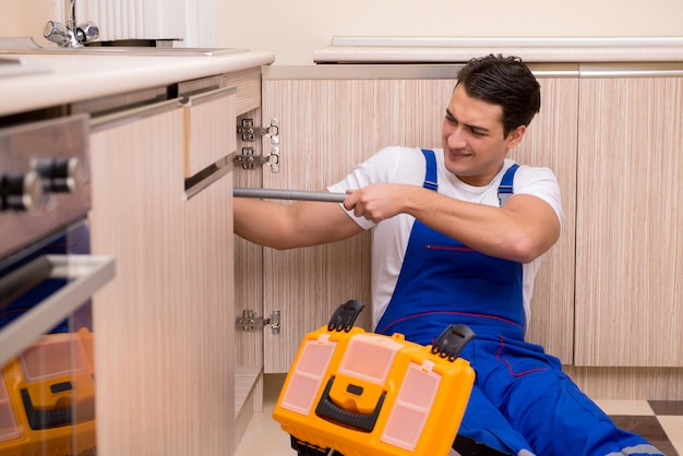 Young repairman working at the kitchen