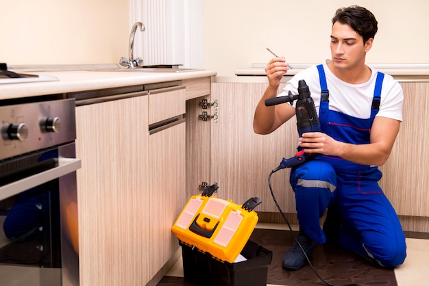 Young repairman working at the kitchen