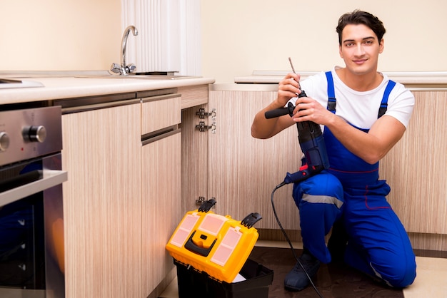 Young repairman working at the kitchen