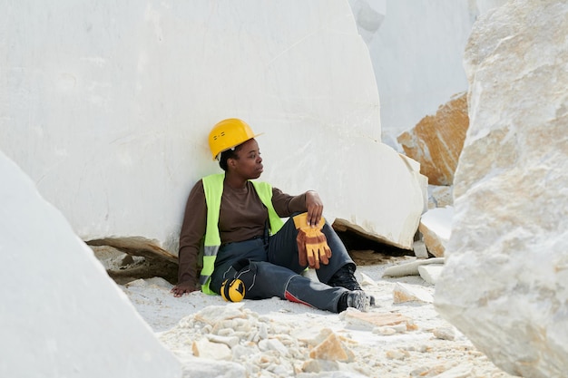 휴식을 취하는 유니폼과 안전 헬멧에 젊은 편안한 여성 노동자