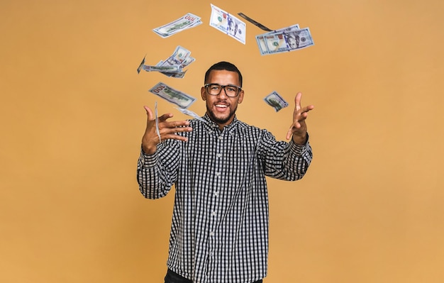 Giovane uomo afroamericano ricco in maglietta casual che tiene banconote da un dollaro con sorpresa