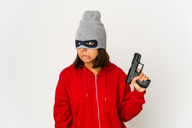 Young robber hispanic woman wearing a mask confused, feels doubtful and unsure.