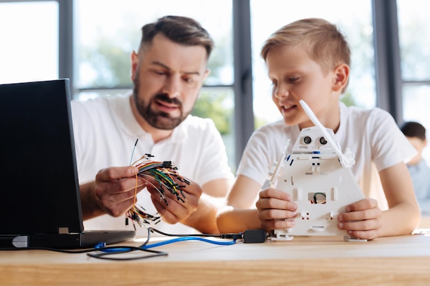 Young robotics teacher sitting at the table with his student
