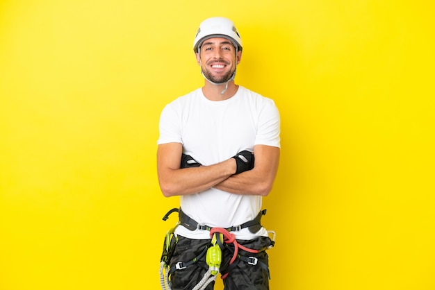Photo young rock- climber man isolated on yellow background keeping the arms crossed in frontal position