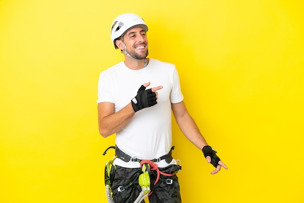 Young rock- climber man isolated on yellow background pointing finger to the side and presenting a product