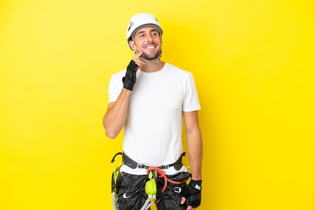 Photo young rock- climber man isolated on yellow background thinking an idea while looking up