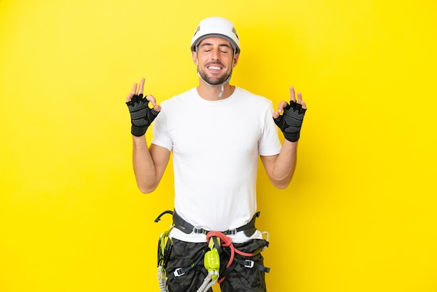 Young rock- climber man isolated on yellow background in zen pose