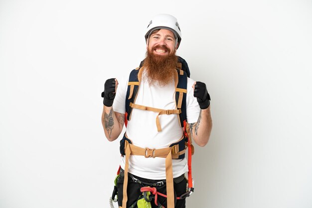 Young rock climber reddish caucasian man isolated on white background celebrating a victory in winner position