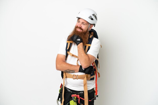 Young rock- climber reddish caucasian man isolated on white background looking to the side and smiling