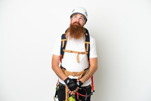 Young rock climber reddish caucasian man isolated on white background and looking up