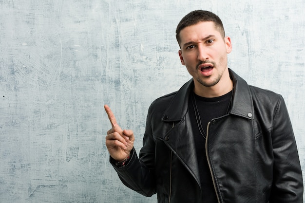 Young rocker man pointing to the side