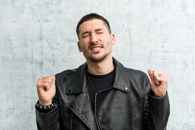 Young rocker man raising fist, feeling happy and successful. Victory .