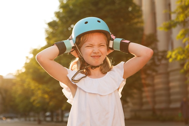 彼女のヘルメットを脱ぐことを試みて、イライラしているように見える若いローラーブレードの女の子