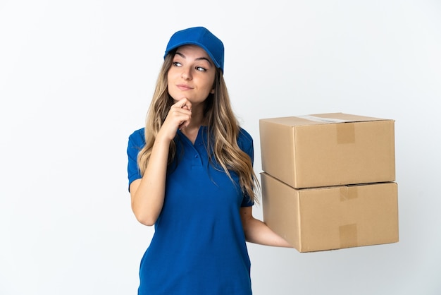 Young Romanian delivery woman isolates on white wall and looking up