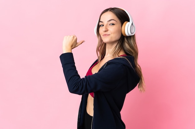 Young Romanian sport woman isolated on pink wall proud and self-satisfied