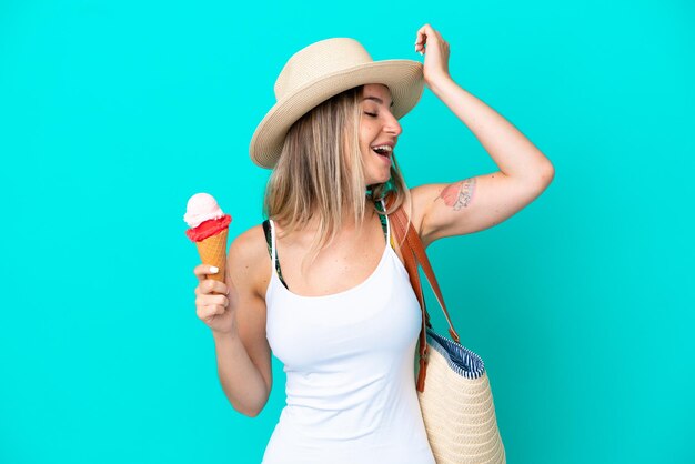 Young Romanian woman holding ice cream and beach bag isolated on blue background has realized something and intending the solution