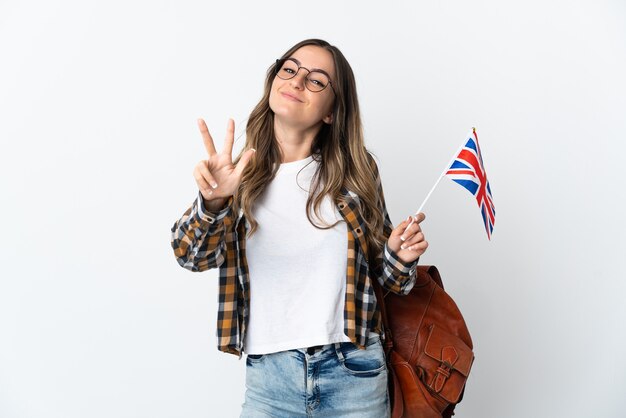 Young romanian woman holding an united kingdom flag on white happy and counting three with fingers