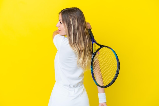 Young romanian woman isolated on yellow background playing tennis