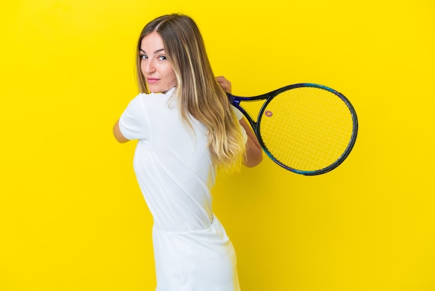 Young romanian woman isolated on yellow background playing tennis