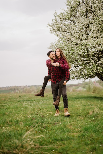 Young romantic couple walking on the meadow and blooming tree and have fun