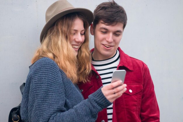 Young romantic couple watching social network contents sharing\
a smartphone screen. people using technology concept