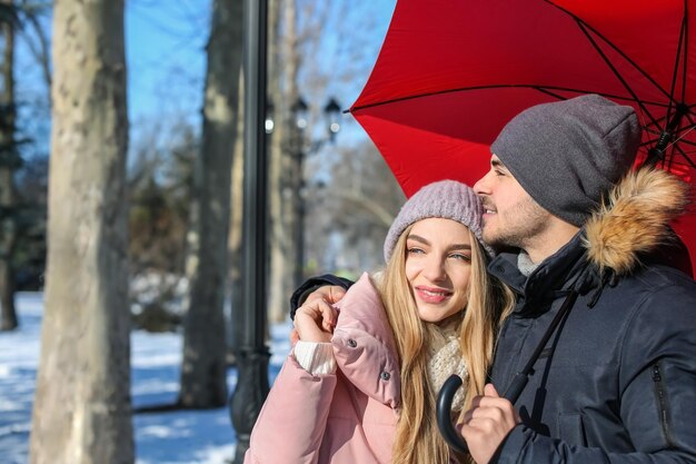 Young romantic couple with bright umbrella on sunny winter day