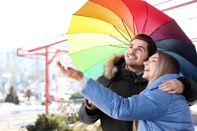 Young romantic couple with colorful umbrella outdoors