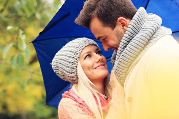 Young romantic couple with umbrella in the park in autumn